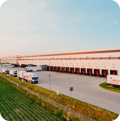 Magazyn Rossmanna z rampami załadunkowymi i zaparkowanymi ciężarówkami